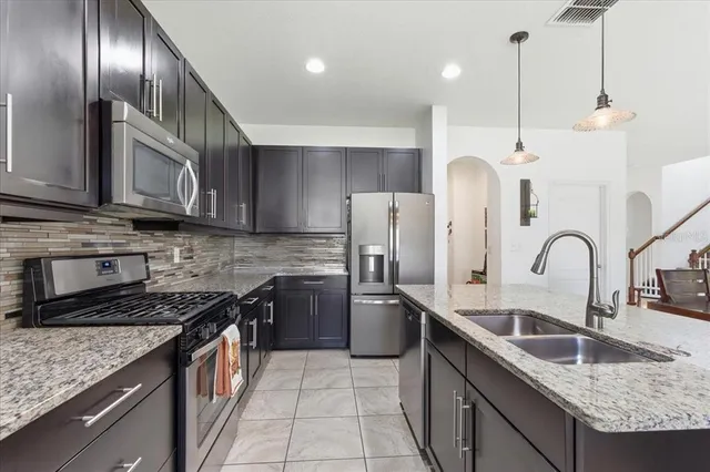 a kitchen with stainless steel appliances granite countertop a sink a stove and a refrigerator