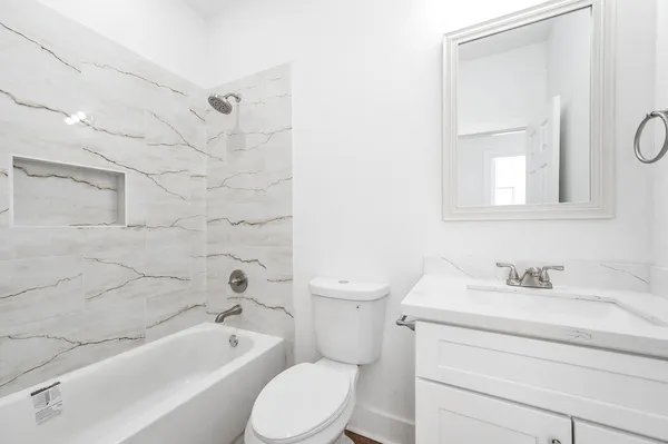 a bathroom with a toilet sink vanity tub and shower
