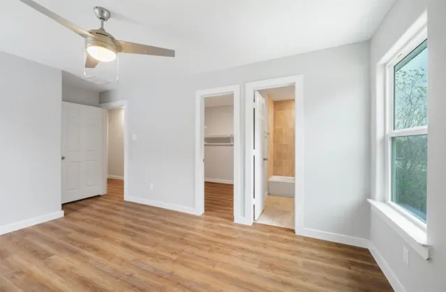 a view of an empty room with wooden floor and a window