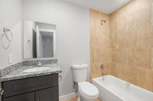 a bathroom with a granite countertop sink a toilet and shower