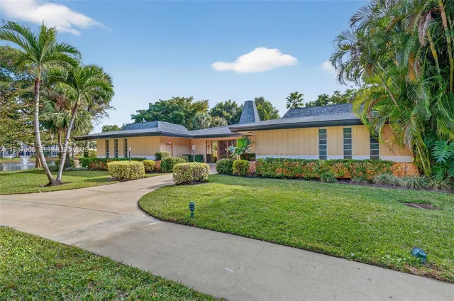 a view of a house with a yard and palm trees