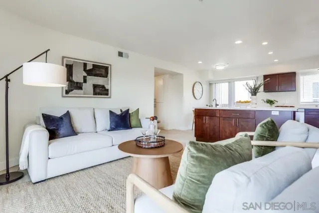 a living room with furniture kitchen view and a flat screen tv