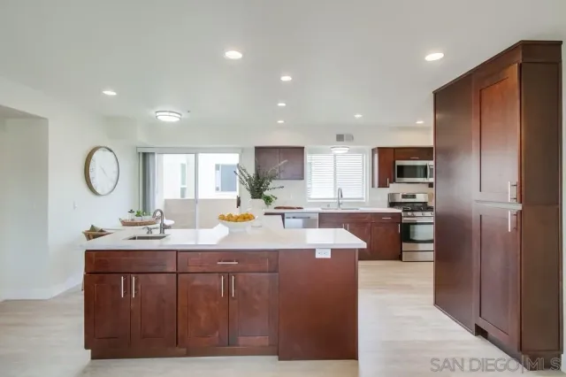 a kitchen with stainless steel appliances kitchen island granite countertop a refrigerator and a sink
