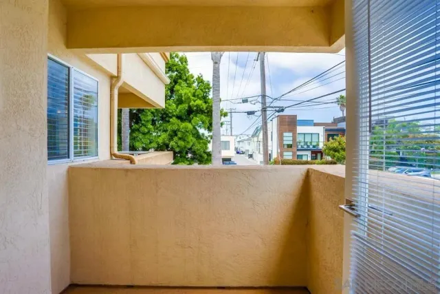 a view of a white house with a small yard and large trees