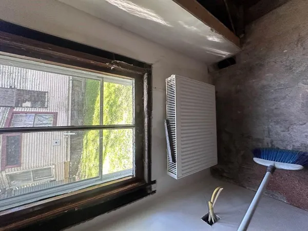 a view of a room with a large window and wooden floor