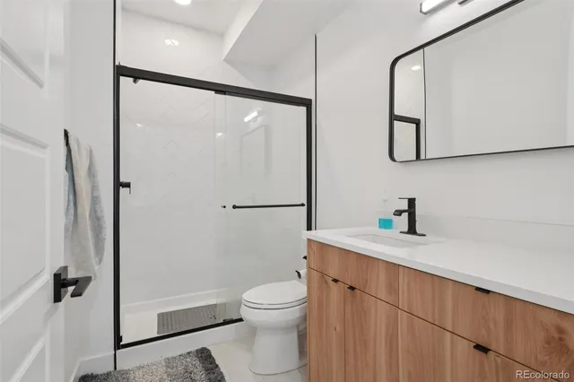 a bathroom with a granite countertop sink toilet a mirror a vanity and shower