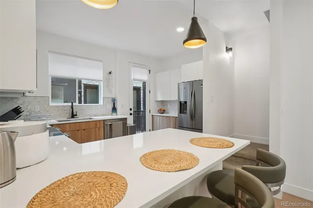 a kitchen with stainless steel appliances granite countertop a dining table chairs and a refrigerator