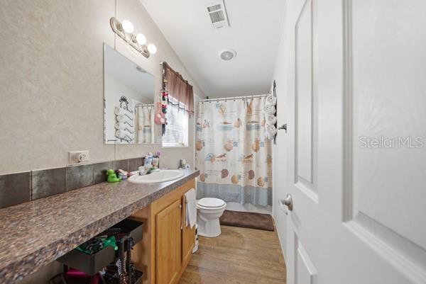 12148 Rutherford Lane Hudson, FL 34669 - Photo 13 of 30 a bathroom with a granite countertop sink a toilet a mirror and shower