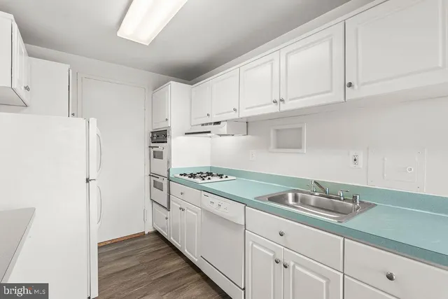 a kitchen with granite countertop a sink stainless steel appliances and white cabinets