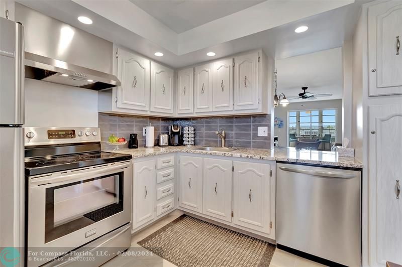 a kitchen with stainless steel appliances granite countertop a stove and white cabinets