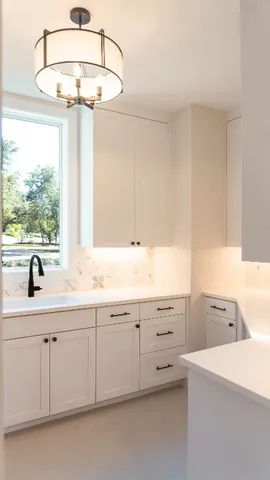 a kitchen with a sink dishwasher and white cabinets with wooden floor