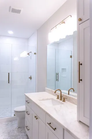 a bathroom with a granite countertop sink toilet and shower