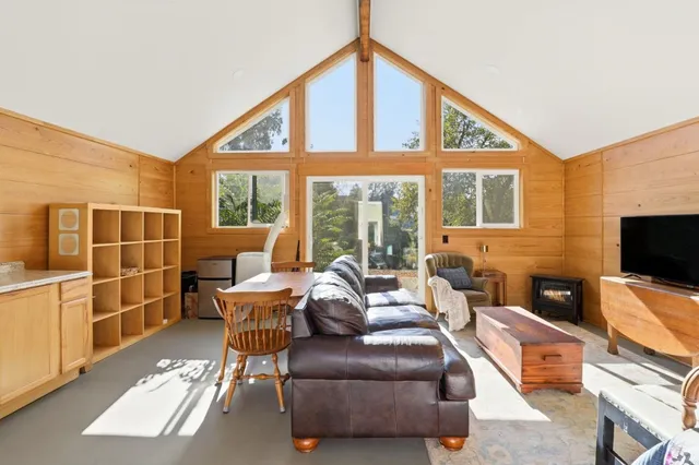 a living room with furniture a flat screen tv and floor to ceiling window