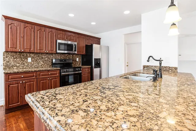 a kitchen with kitchen island granite countertop a sink stove and refrigerator