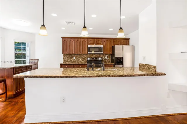 a kitchen with granite countertop a sink a counter top space and cabinets