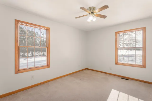 an empty room with windows and fan