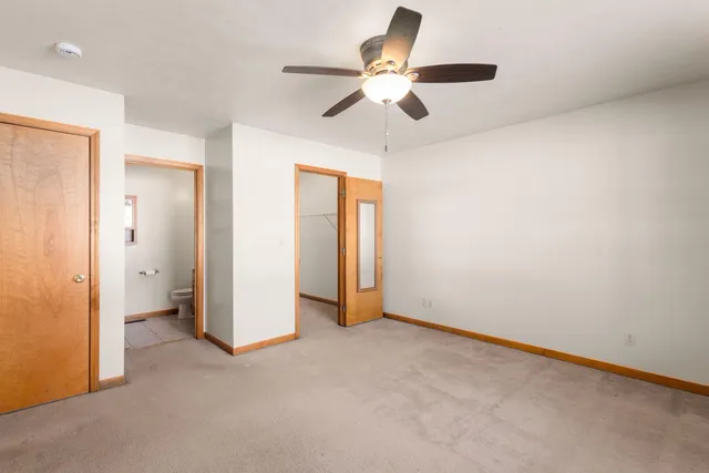 an empty room with closet and a chandelier fan