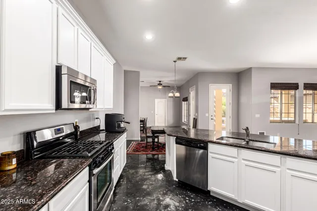 a kitchen with stainless steel appliances granite countertop a stove a sink and a microwave