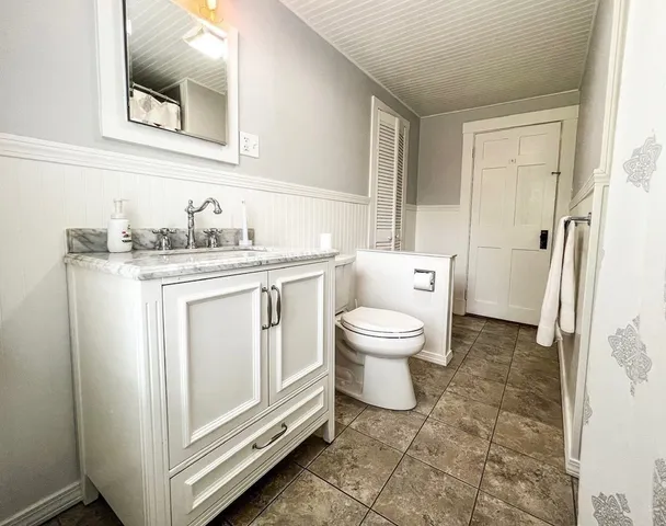 a spacious bathroom with a granite countertop toilet sink and mirror