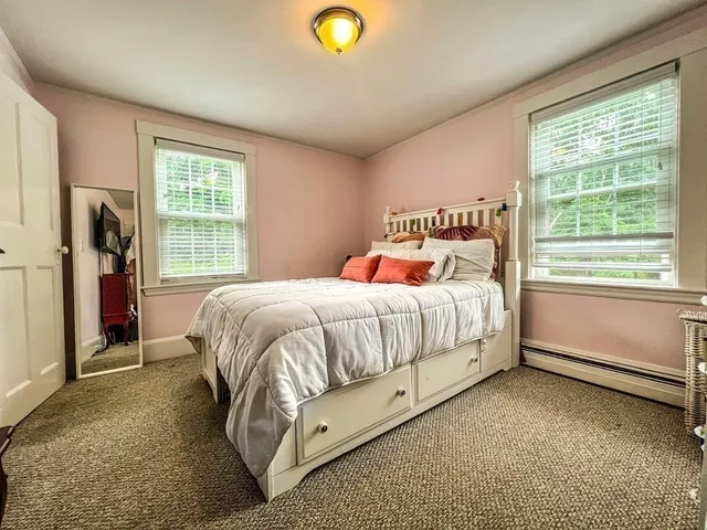 a bed sitting in a spacious bedroom next to a window