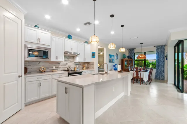 a kitchen with kitchen island a dining table chairs and a sink