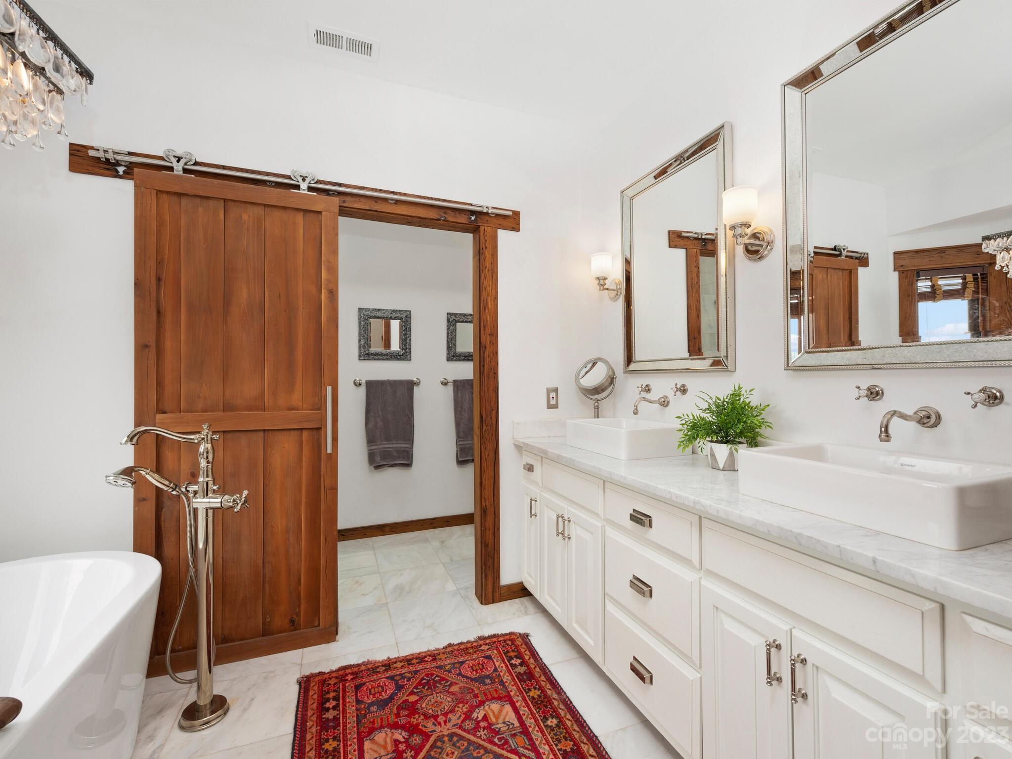 574 Golden Road Columbus, NC 28722 - Photo 32 of 48 a spacious bathroom with a double vanity sink a mirror and a shower
