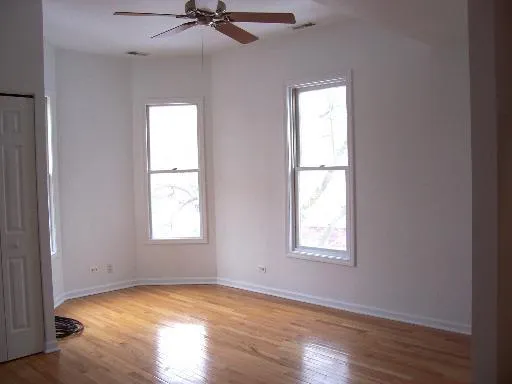 an empty room with wooden floor closet and windows