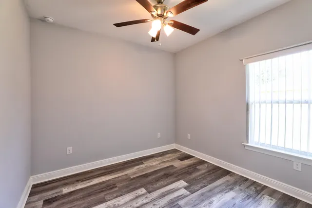 an empty room with windows and fan