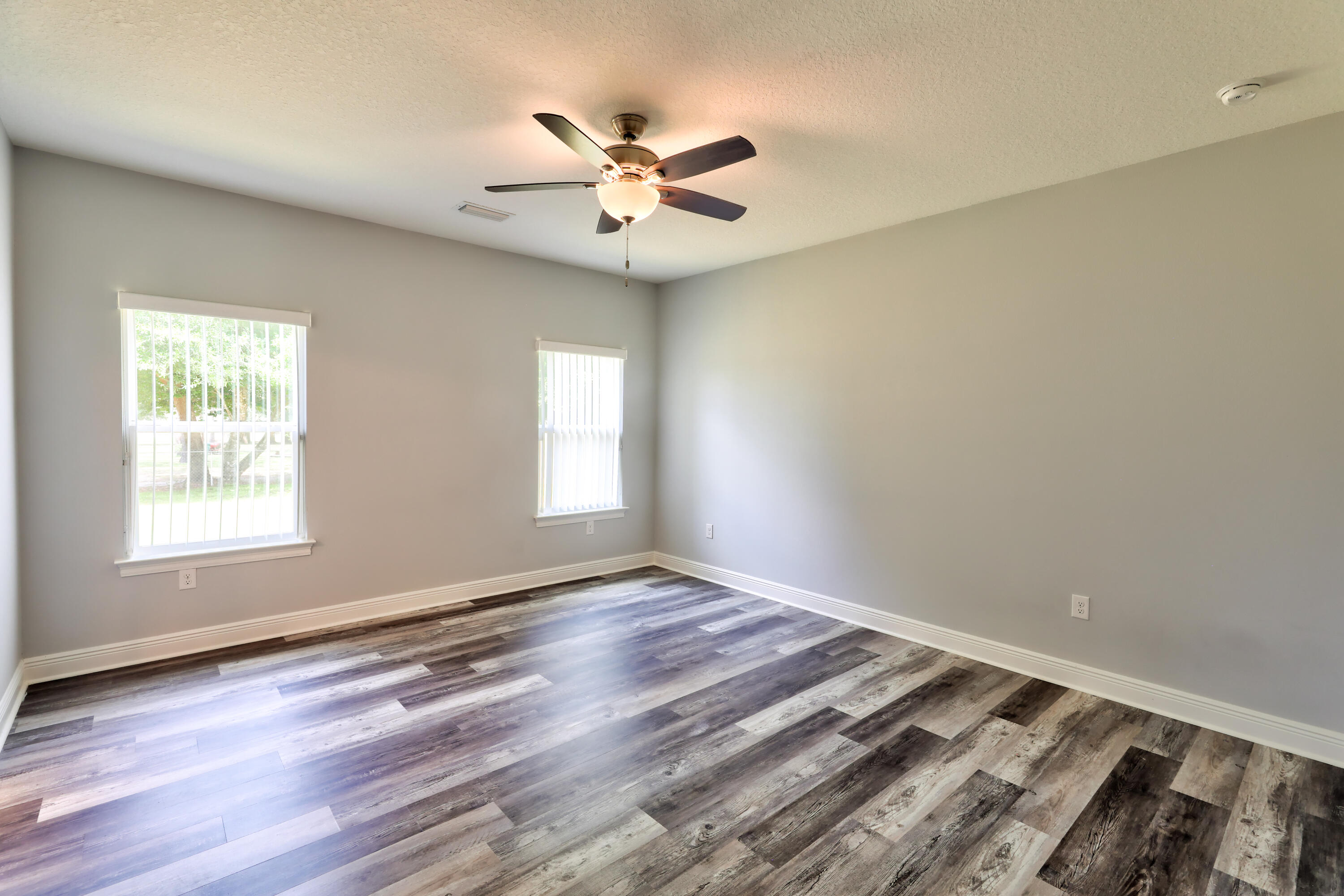 6160 Hayes Drive Crestview, FL 32539 - Photo 31 of 45 an empty room with wooden floor fan and windows