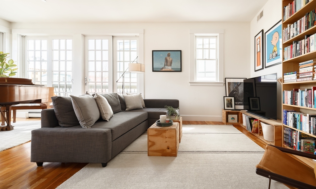 80 Webster Avenue, Unit 2A Somerville, MA 02143 - Photo 2 of 19 a living room with furniture a flat screen tv and a book shelf