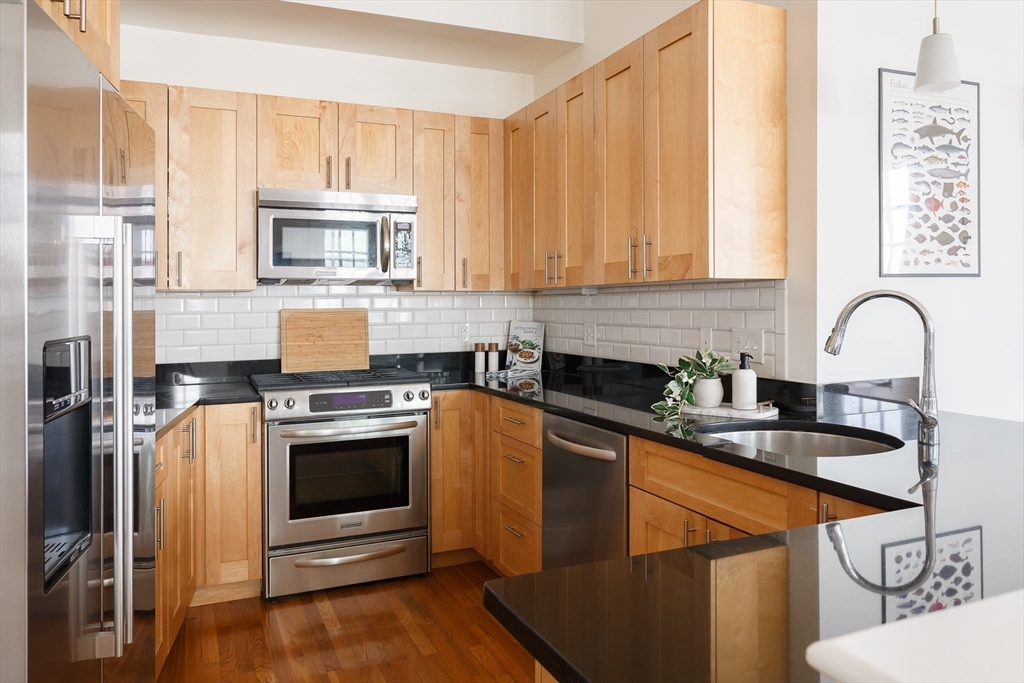 80 Webster Avenue, Unit 2A Somerville, MA 02143 - Photo 4 of 19 a kitchen with stainless steel appliances granite countertop a stove a sink dishwasher and a microwave oven with cabinets