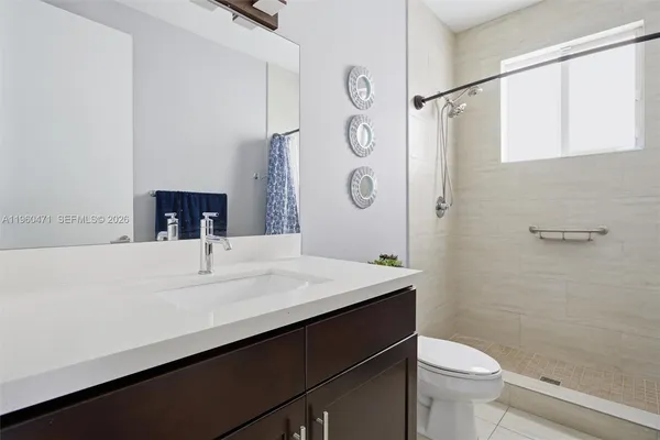 a bathroom with a sink a toilet a mirror and shower