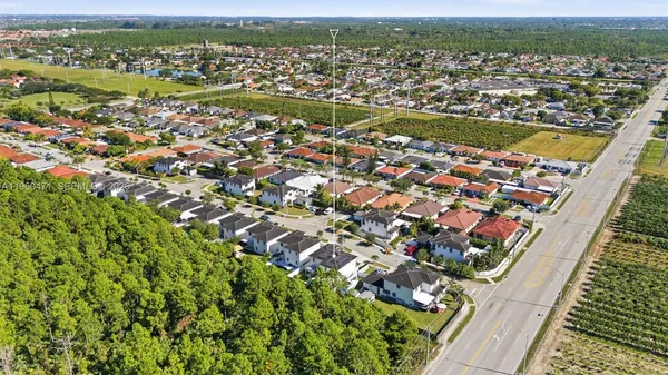 an aerial view of residential houses with outdoor space and trees