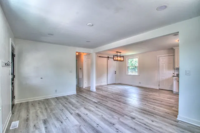a view of an empty room with window and wooden floor