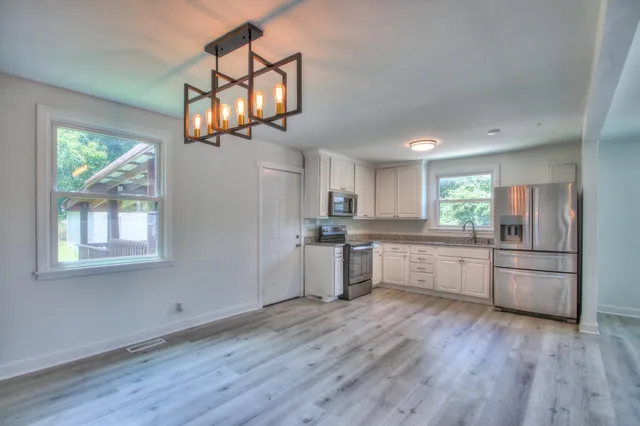 a kitchen with stainless steel appliances granite countertop a refrigerator a stove top oven a sink dishwasher and wooden floor