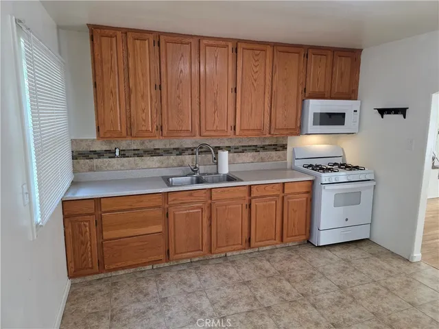 a kitchen with granite countertop a sink a stove and cabinets
