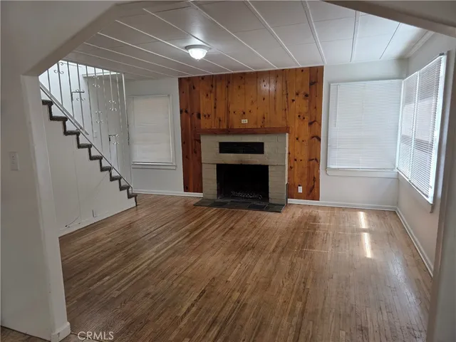 a view of an empty room with wooden floor fireplace and a window