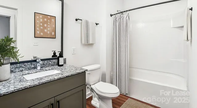 a bathroom with a granite countertop sink toilet and shower