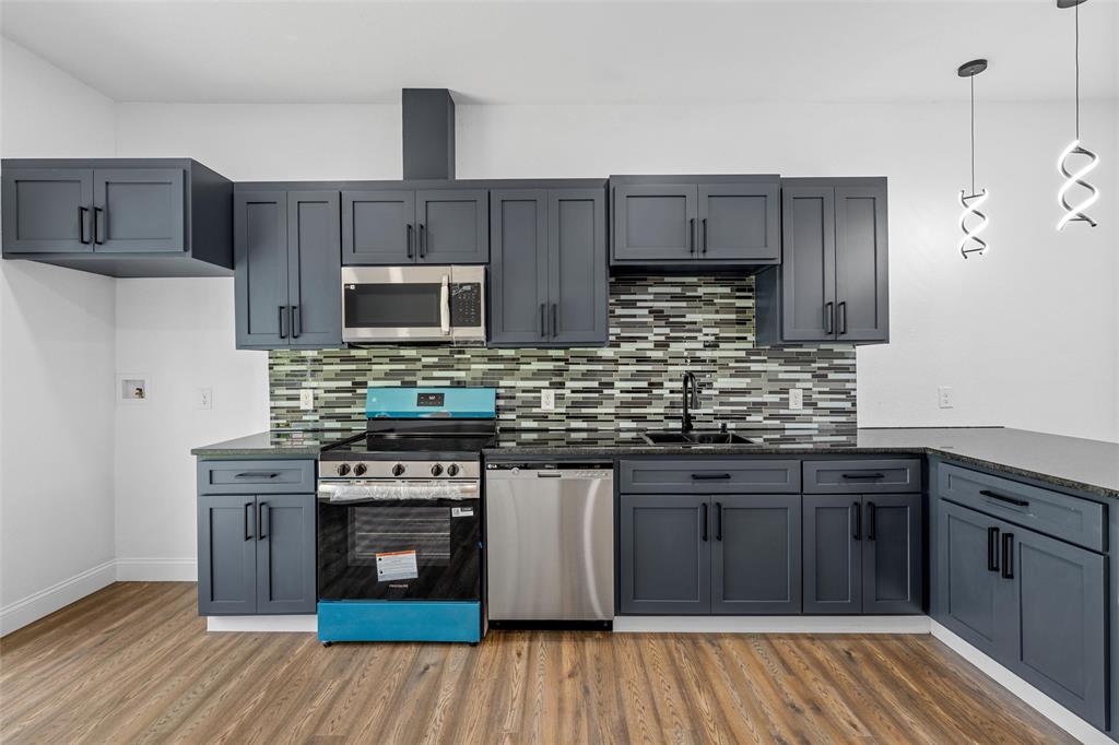 2023 Bosque Boulevard Waco, TX 76707 - Photo 10 of 26 Modern kitchen featuring dark cabinetry with black hardware, stainless steel appliances, and a mosaic tile backsplash