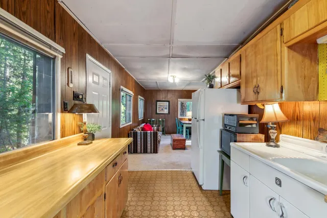 a view of a kitchen with kitchen island a large window cabinets a sink and stainless steel appliances