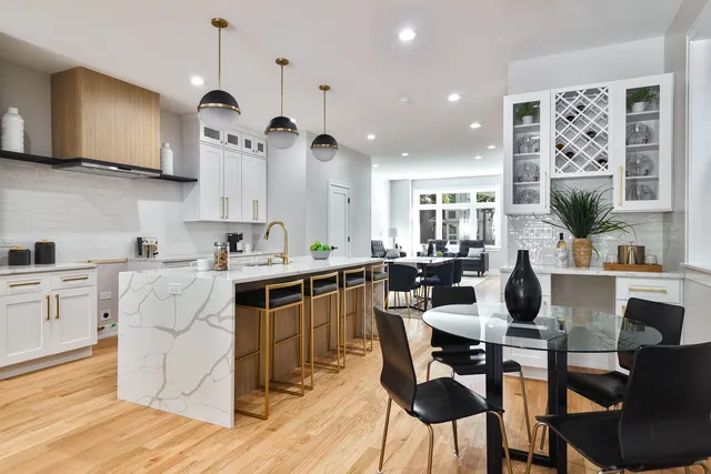 a kitchen with stainless steel appliances kitchen island granite countertop a stove a sink a dining table and chairs with wooden floor