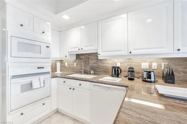 a kitchen with granite countertop a sink a stove and cabinets