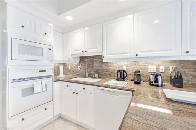 a kitchen with granite countertop a sink a stove and cabinets