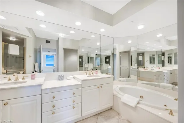 a bathroom with a sink double vanity granite tub shower and a mirror