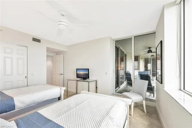 a bedroom with two beds and large windows