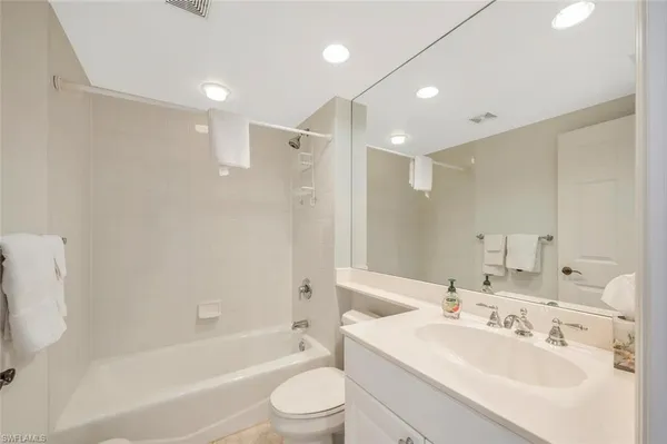 a bathroom with a bathtub shower sink vanity mirror and toilet