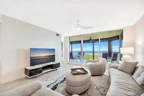 a living room with furniture a large window and flat screen tv