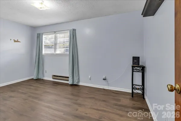 an empty room with wooden floor closet and windows