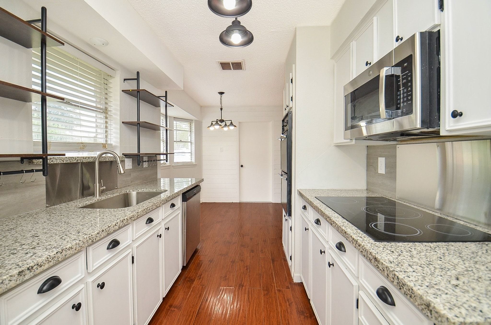 9014 Langfield Road Houston, TX 77040 - Photo 15 of 37 A large arched window floods the workspace with natural light, while trendy open industrial shelving above the sink adds stylish storage and display options. This kitchen is fully equipped with stainless steel appliances!