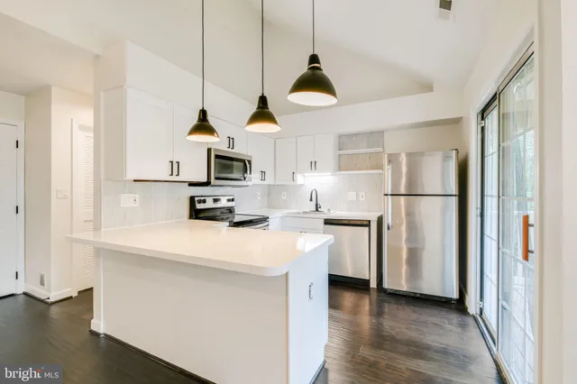 a kitchen with stainless steel appliances a refrigerator a stove a sink dishwasher and a refrigerator with wooden floor